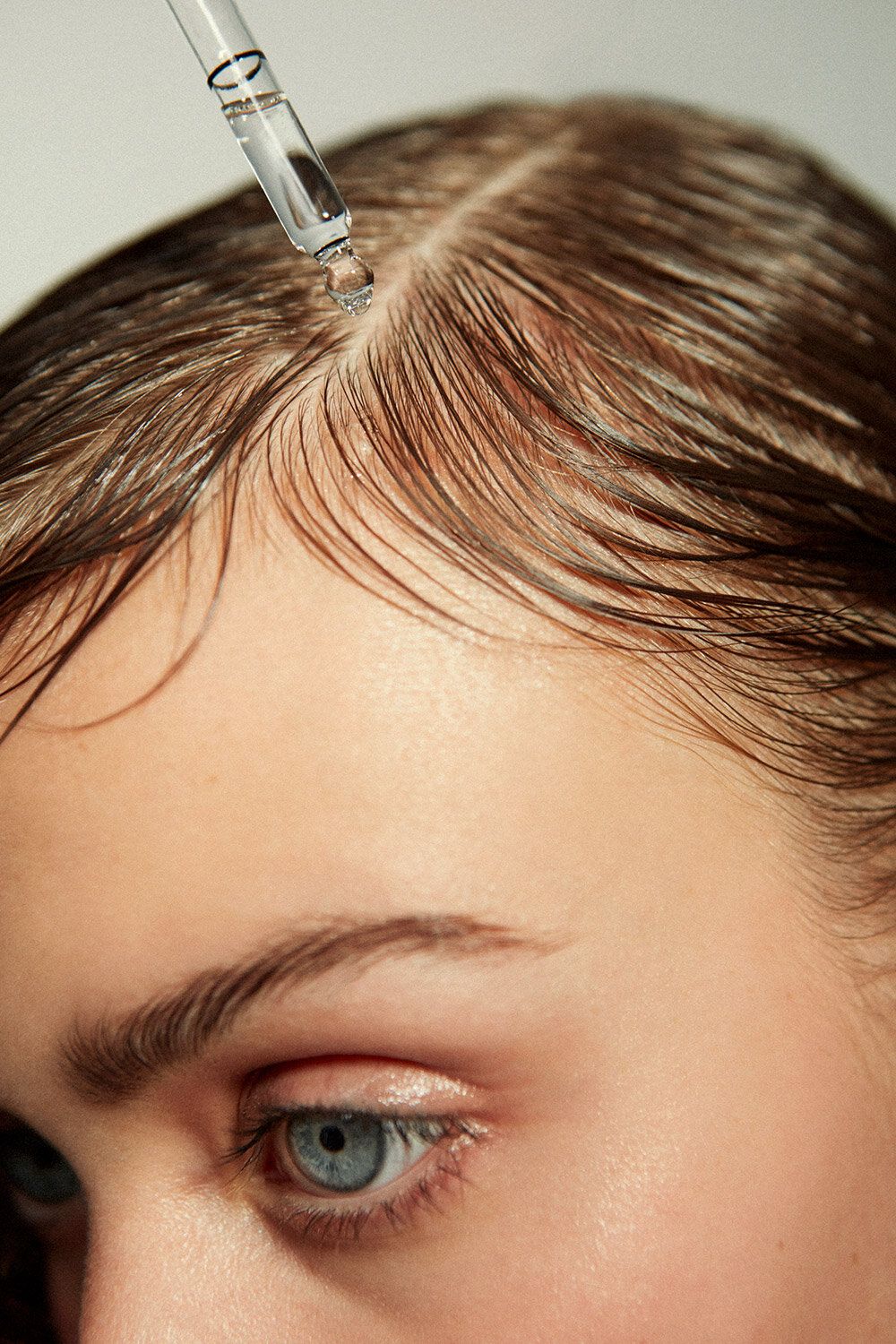 Aplicação de sérum com conta-gotas em cabelo cacheado